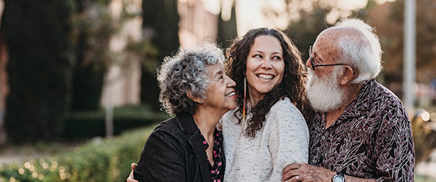 Senior couple smiling and hugging adult woman