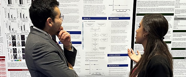 Two people discuss a poster presentation