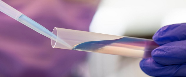 Gloved hands pipetting liquid in a test tube