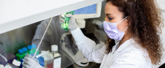 Research associate pipetting fluid for lab experiment