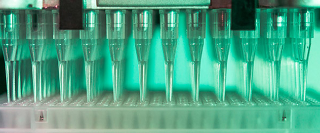 Close-up view of the lab's automated pipetting system, shown in a green light.