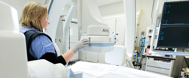 A person uses a Siemens Artis zee biplane fluoroscopy system.