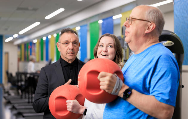 Dr. Benzo guiding two people in a rehabilitation class